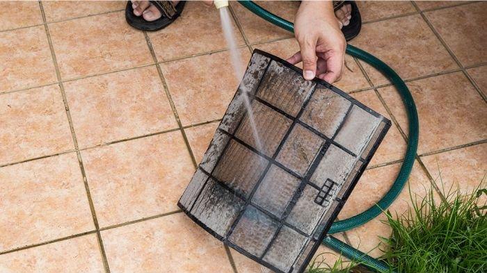 Ilustrasi filter AC dibilas dengan air mengalir