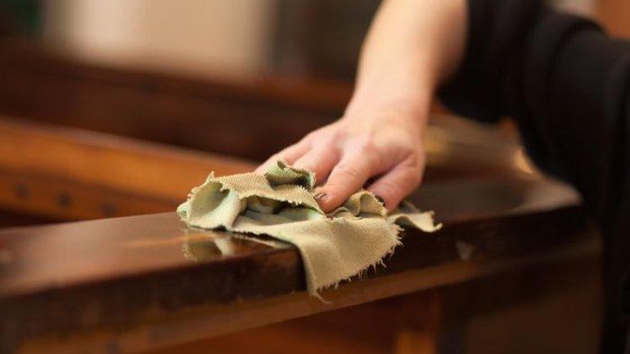 Ilustrasi membersihkan furnitur kayu secara berkala untuk menjaga kilaunya, serta memastikan tidak ada debu yang menempel di permukaan supaya tidak memicu keropos.