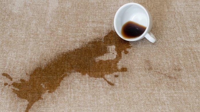 Ilustrasi noda kopi yang menempel di atas permukaan sofa kain.