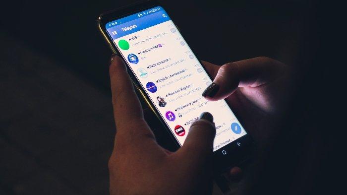 Ilustrasi pengguna HP membuka aplikasi Telegram