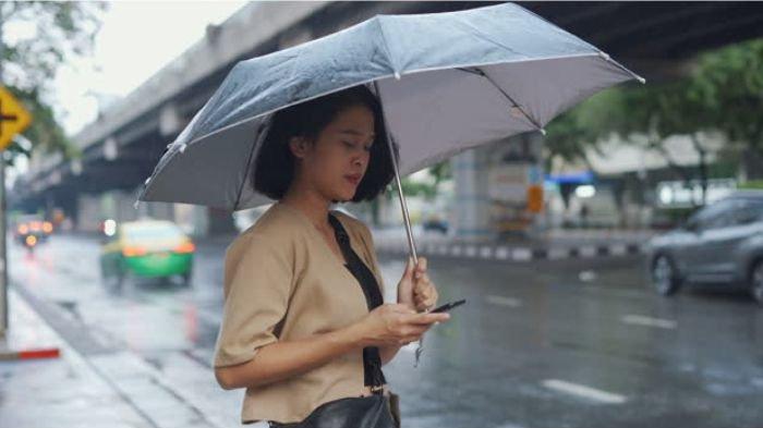 Ilustrasi memakai HP di bawah rintik hujan