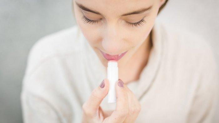 Ilustrasi perempuan yang mengoleskan lipstik pada bibir.