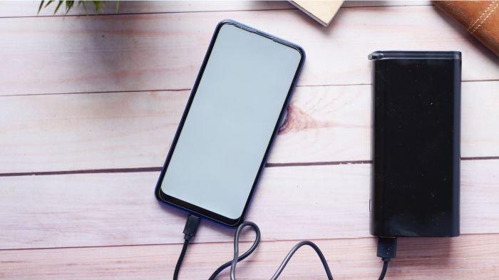Ilustrasi powerbank yang sedang dipakai mengecas HP