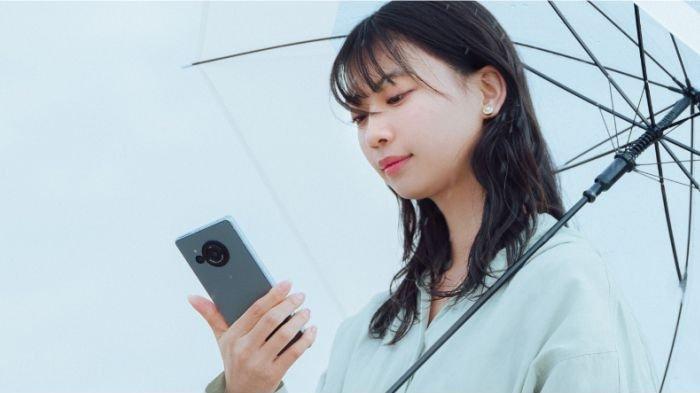 Ilustrasi seorang wanita yang sedang memegang HP flagship Ilustrasi SHARP AQUOS R8s