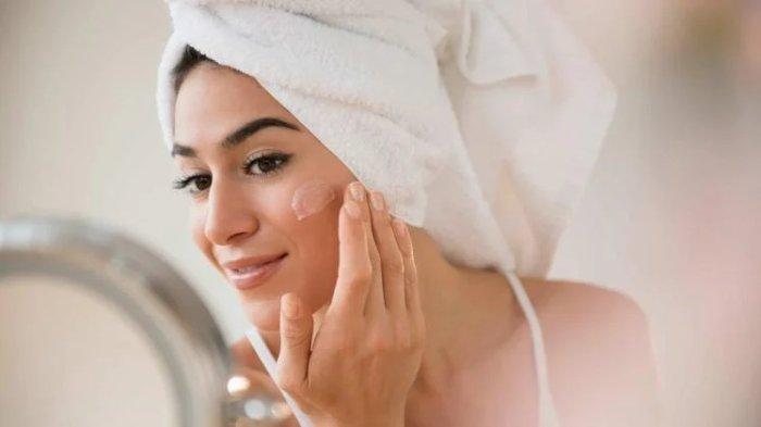 Ilustrasi wanita mengaplikasikan moisturizer pada kulit wajah secara teratur saat musim kemarau.