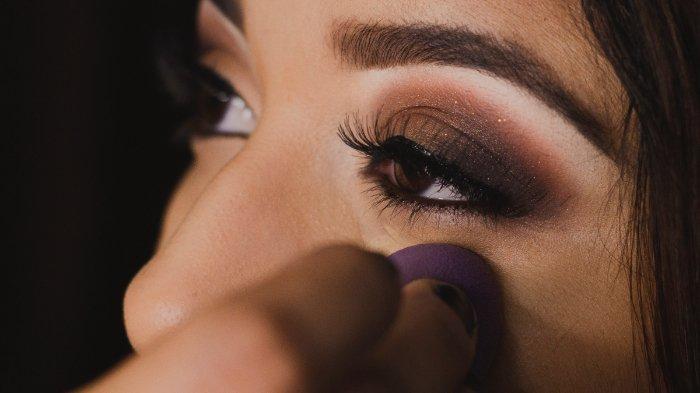 Ilustrasi wanita menggunakan eyeshadow dengan warna gelap.