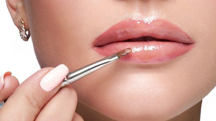 Ilustrasi wanita menggunakan lip gloss.