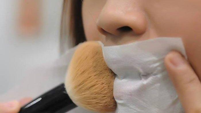 melakukan teknik blotting dengan set menggunakan bedak di bibir.