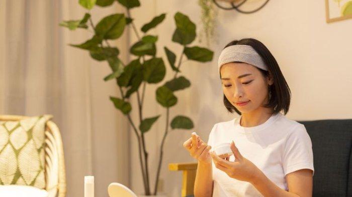 Ilustrasi seorang wanita mengaplikasikan produk perawatan kulit wajah.
