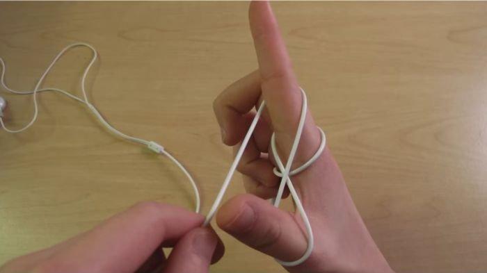 Ilustrasi menggulung kabel headset dan earphone dengan bantuan jari tangan yang membentuk pistol