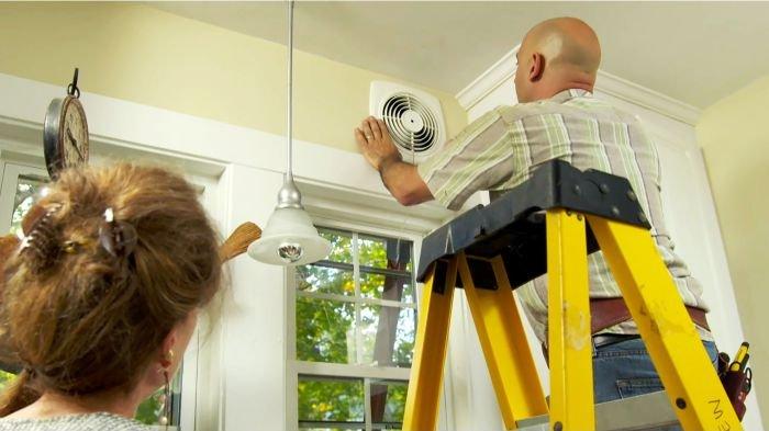 Ilustrasi seorang pria sedang memasang exhaust fan di dapur.