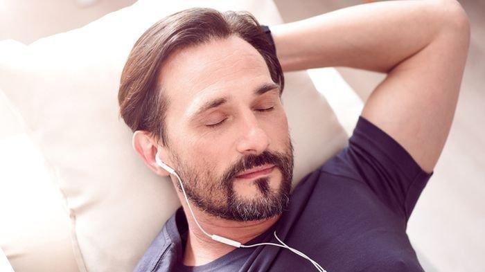 Ilustrasi seorang pria tidur dengan menggunakan headset untuk memutar musik