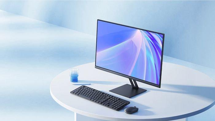 Ilustrasi Xiaomi Monitor A24i yang diletakkan di atas meja kerja kantoran