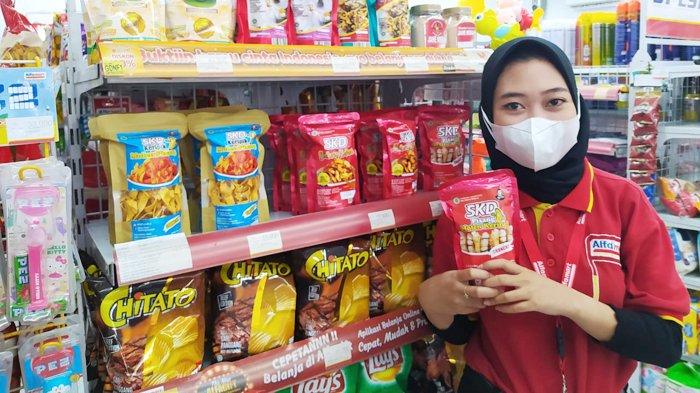 Karyawan Alfamart menunjukan produk ukm yang dipamerkan di rak etalase retail.