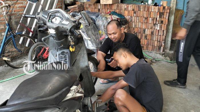MOGOK. Warga Jaten, Karanganyar, Maulana Surya saat mereparasi motornya Honda Revo yang mogok usai mengisi BBM jenis Pertalite di SPBU Pucangsawit. Ini sudah kejadian kedua kasus yang sama.