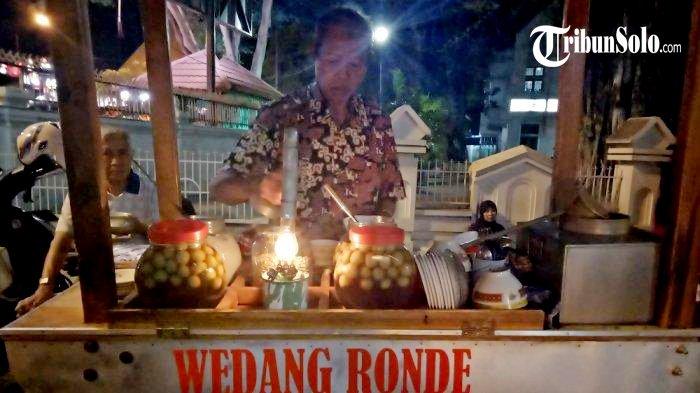 Pak Darto sedang menyiapkan pesanan wedang ronde di gerobaknya yang berlokasi di Jl. Arifin No.  1, Solo