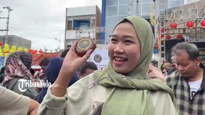 KEMERIAHAN GREBEG SUDIRO - Ekspresi senang seorang pengunjung mendapatkan kue keranjang saat Karnaval Budaya Grebeg Sudiro 2025 di Pasar Gede Solo, Jateng, Minggu (26/1/2025) siang.