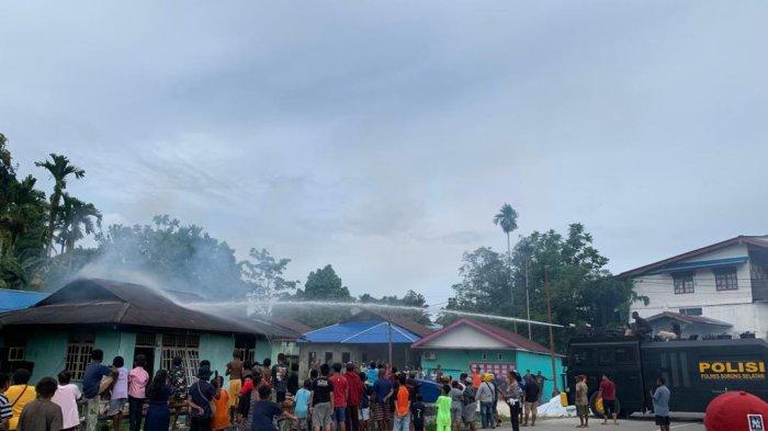 Polisi melakukan pemadaman api di rumah warga yang terbakar di Kampung Wermit, Teminabuan, Kabupaten Sorong Selatan.