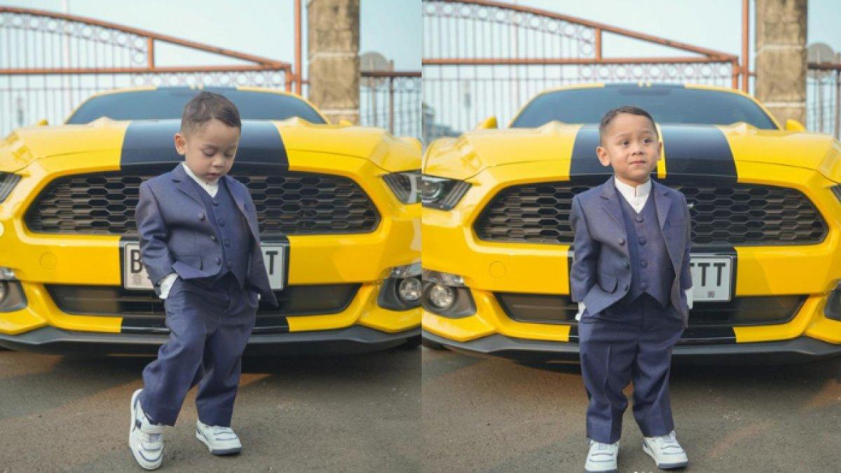 Abang L tampil kece memakai setelan jas dengan background mobil sport