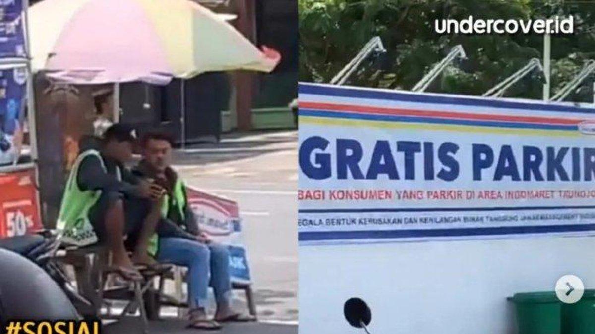 Aksi santai tukang parkir tetap nongkrong di minimarket meski ada spanduk gratis parkir.