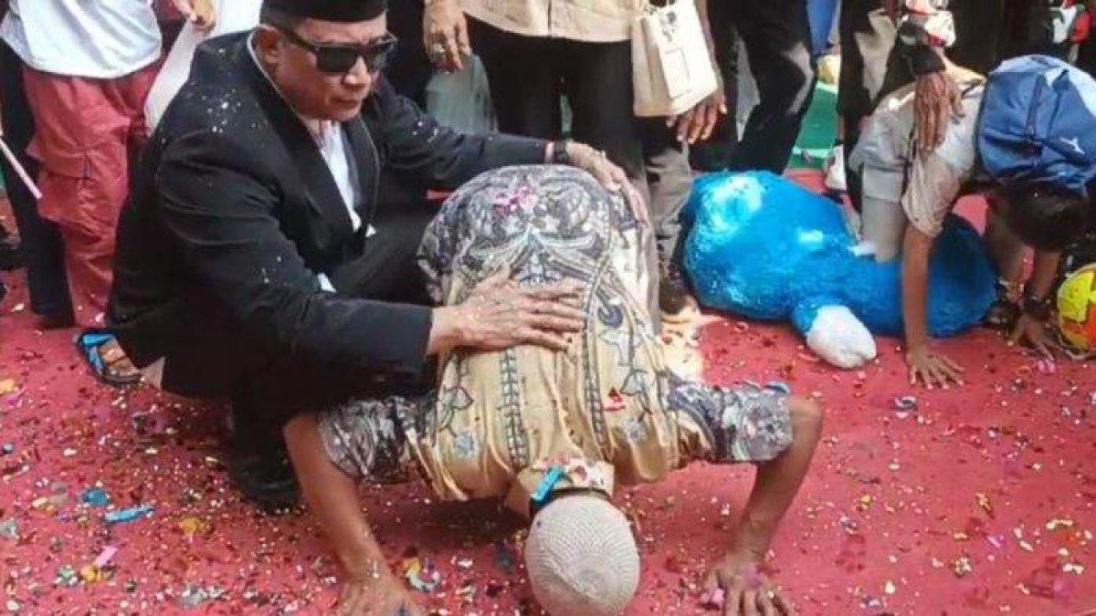 Ato melakukan sujud syukur saat gunting pita rumah baru didampingi H. Isep Dadang Sukmana