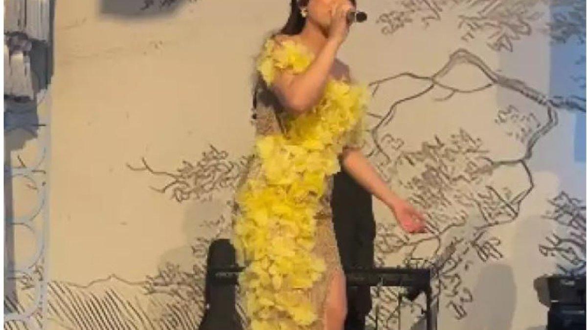 Happy Asmara terlihat mengenakan dress ketat bermotif warna emas dengan hiasan bunga kuning di bagian depan.