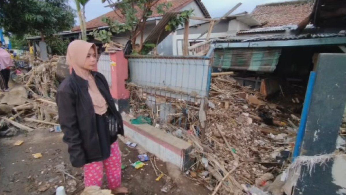 Kustini mengorek tumpukan sampah yang terbawa banjir dengan harapan bisa menemukan motor matiknya