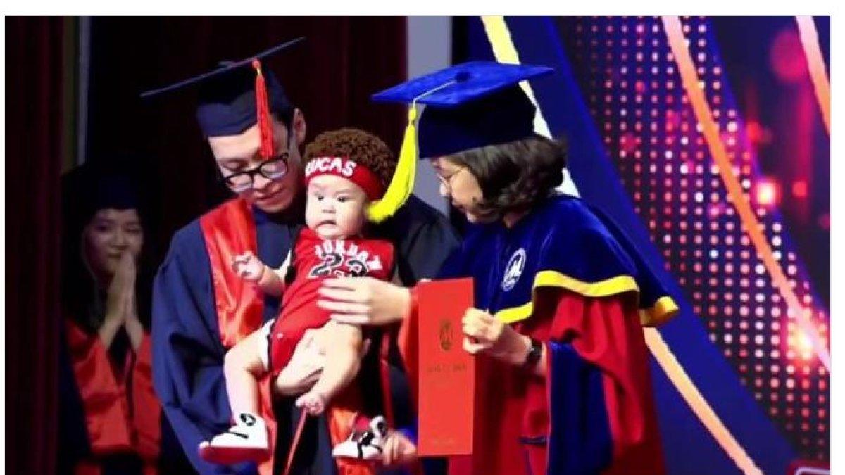 Mahasiswa laki-laki Nguyen Hoang Vinh, 22 tahun, menggendong putranya yang tampan dan menggemaskan untuk menerima diploma pada upacara wisuda di Universitas Keuangan dan Pemasaran.