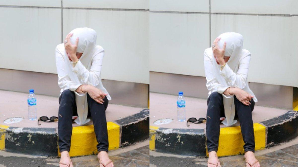 Olla Ramlan tampak duduk di sebuah trotoar