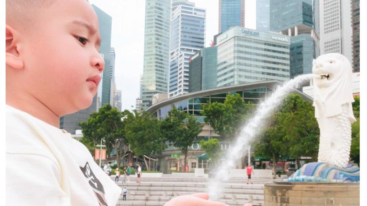Selain bergaya minum air hingga mengisi botol air, Rayyanza kembali memamerkan gayanya seolah-olah sedang berwudhu di depan patung Merlion.
