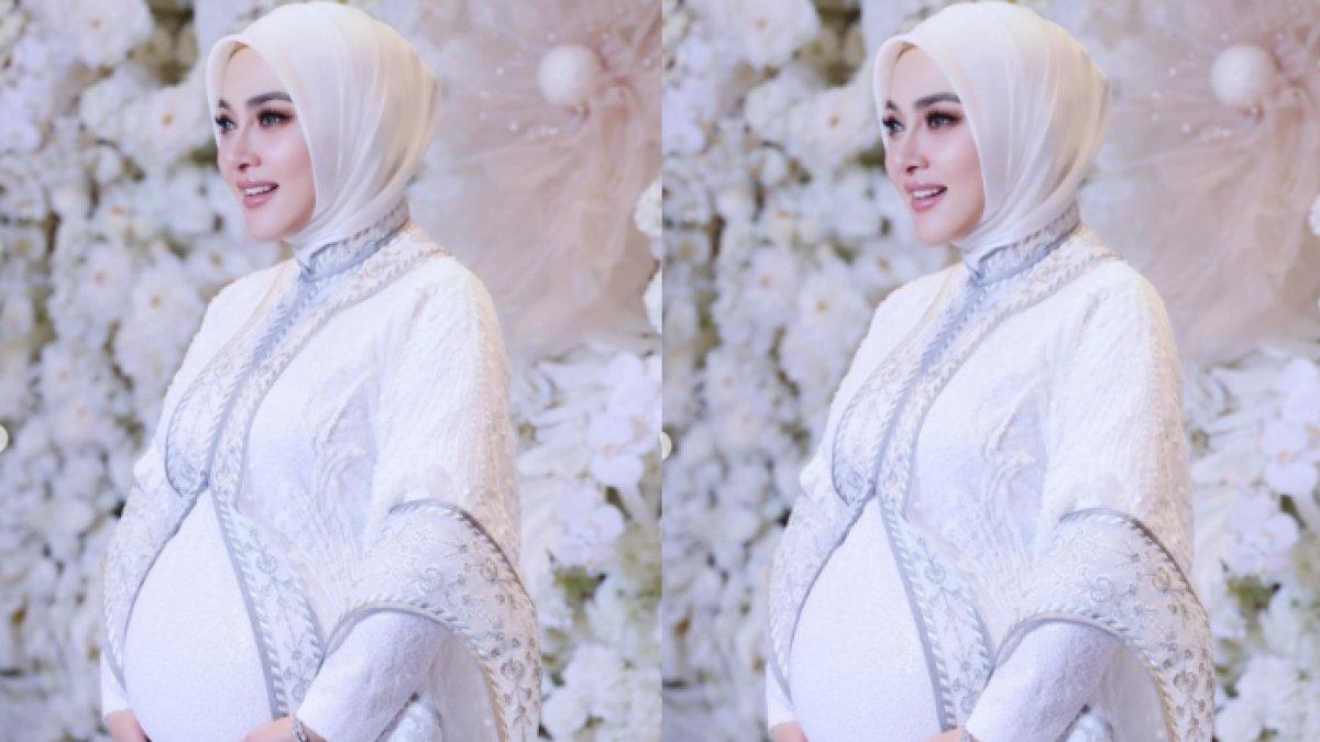 Syahrini berdiri sambil memegang baby bump