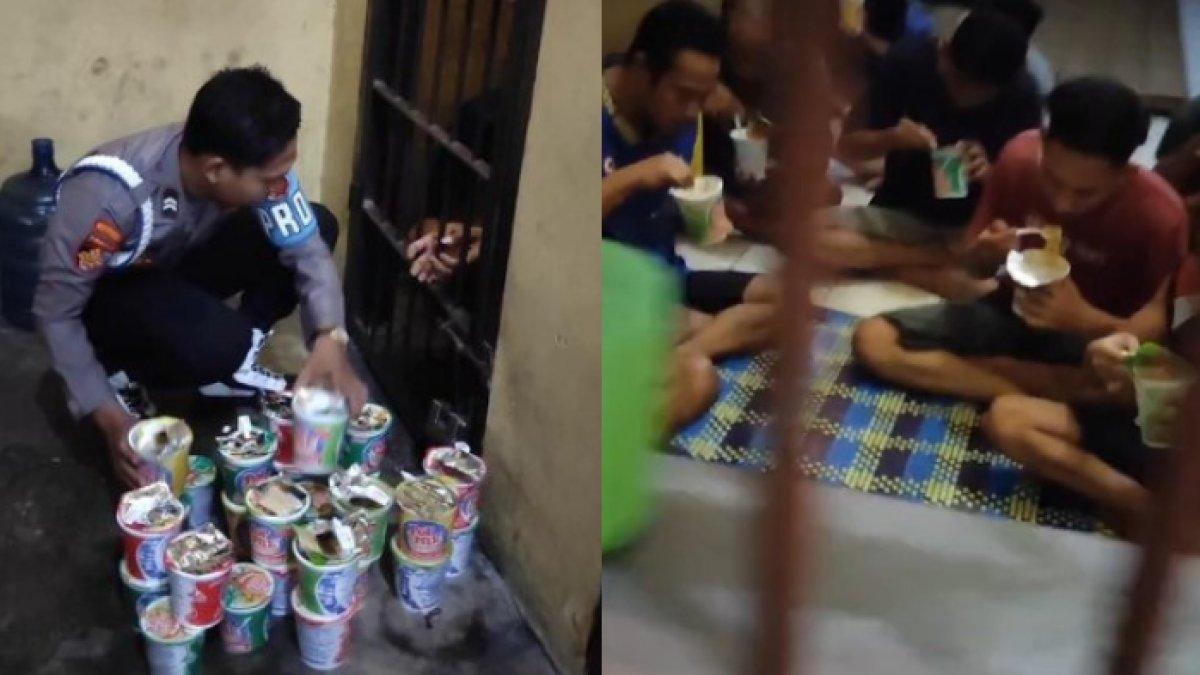 Tampak pak polisi membagikan mie instan pada para tahanan
