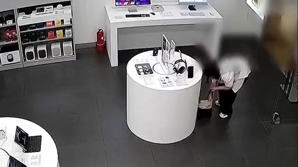 Wanita itu berhasil lepaskan HP dari kabel pengaman lalu dimasukkan ke tas.