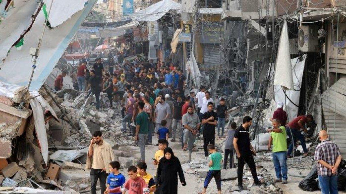 Warga Palestina berjalan di tengah puing-puing bangunan yang hancur dan rusak di pusat kota Khan Yunis yang dibombardir hebat di Jalur Gaza selatan setelah penembakan Israel semalaman, pada 10 Oktober 2023.