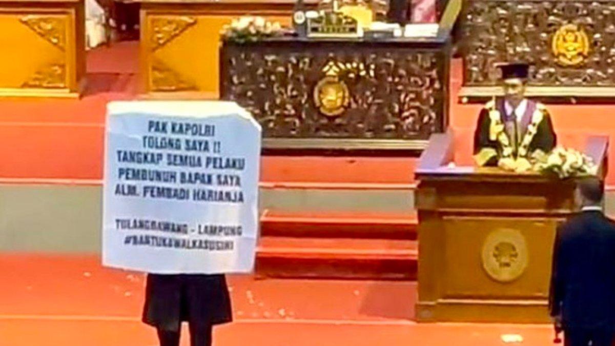 Wisudawan UNM membentangkan spanduk agar polisi mengusut kasus pembunuhan ayahnya