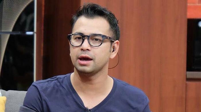 Raffi Ahmad berdiri di tengah panggung dengan pakaian formal dan senyum ramah