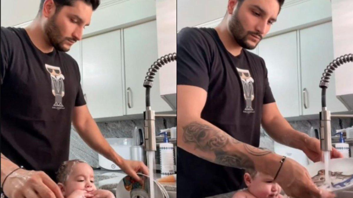 Seorang ayah yang memandikan bayinya sambil cuci piring