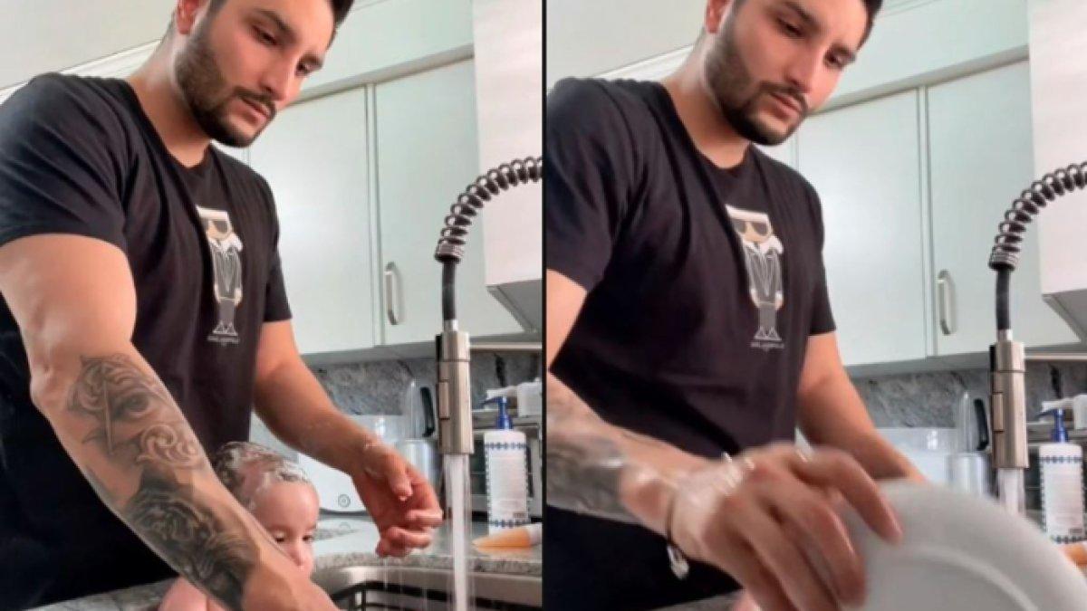 Seorang ayah yang memandikan bayinya sambil cuci piring