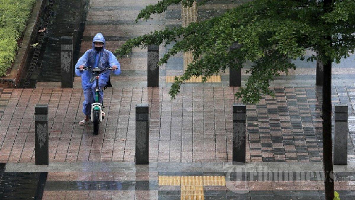 Warga menaiki sepeda listrik melintas saat turun hujan di Jalan Jenderal Sudirman, Jakarta, Rabu (6/10/2021). Kepala Badan Meteorologi Klimatologi dan Geofisika (BMKG), Dwikorita Karnawati mengungkapkan, intensitas hujan akan meningkat pada bulan Oktober dan akan mencapai puncaknya pada bulan Januari dan Februari 2022.