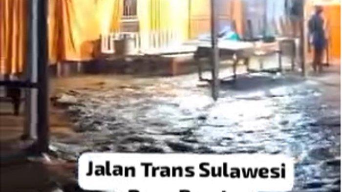 Warga sedang berdiri di depan sebuah bangunan sembari memandangi area jalan di Desa Bambu Mamuju ayng telah digenangi air hujamn