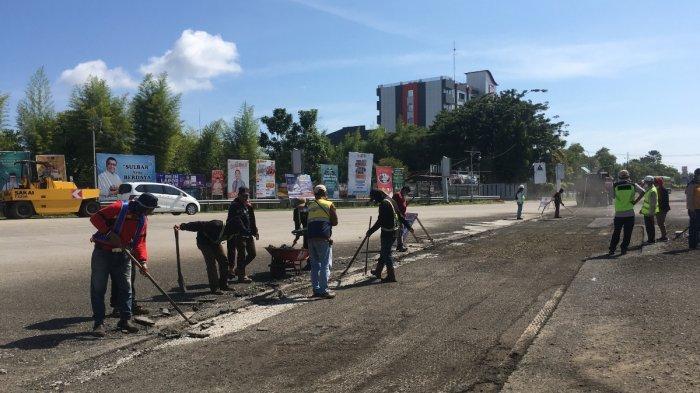 Para pekerja sedang memperbaiki jalananan di persimpangan Jl Yos Sudarso tembusan Jl Arteri karena akan dilalui iring-iringan mobil Presiden Joko Widodo, Sabtu (20/4/2024).
