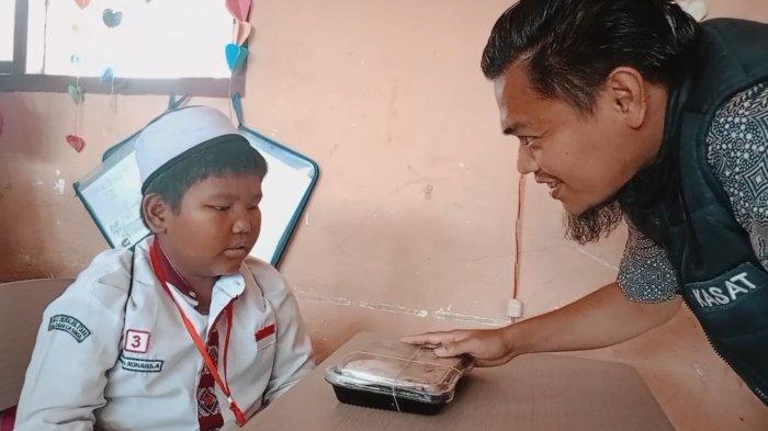 Kasat Reskrim Polres Ogan Ilir AKP Muhammad Ilham membagikan makanan kepada Danang, pelajar kelas III SDN 02 Indralaya Utara, Jumat (29/11/2024) lalu.