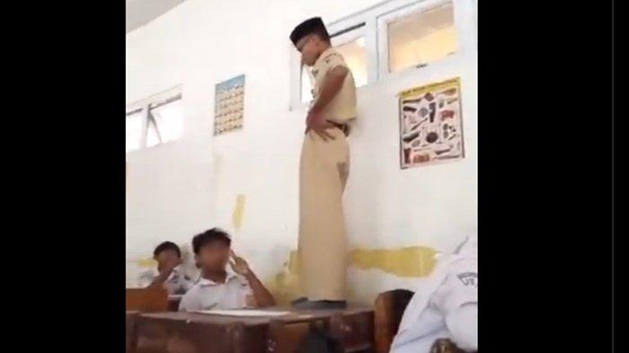 GURU TENDANG SISWA - Seorang guru terlihat berdiri di atas meja dan menendang kepala seorang murid dua kali sambil bergumam, dipicu suara siulan saat ujian semester akhir.
