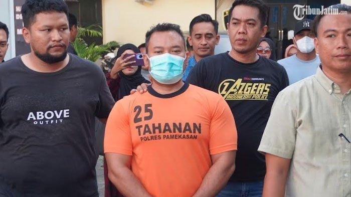 ASN ANIAYA KURIR- Zainal Arifin, seorang Pegawai Negeri Sipil (PNS) di Kabupaten Sampang, Madura yang sempa viral melakukan penganiyaan terhadap kurir paket kini ditangkap, potret saat digiring masuk ke ruang tahanan Polres Pamekasan, Madura, Rabu (2/7/2025).