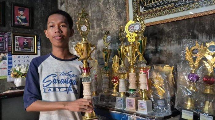 DITERIMA ITB - Avan Ferdiansyah Hilmi, anak penjual es keliling asal Ponorogo diterima ITB di rumahnya, Jalan Bali, Kelurahan Mangkujayan, Kecamatan/Kabupaten Ponorogo, Jatim, Selasa (8/7/2025) saat menunjukkan piala yang didapatkannya selama sekolah.