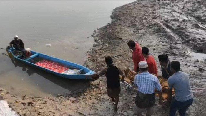 Keluarga dengan dibantu warga saat menggotong jenazah ke perahu kecil milik nelayan, menuju pulau Desa Marparan, Kecamatan Sreseh, Kabupaten Sampang, Madura, Kamis (11/1/2024)