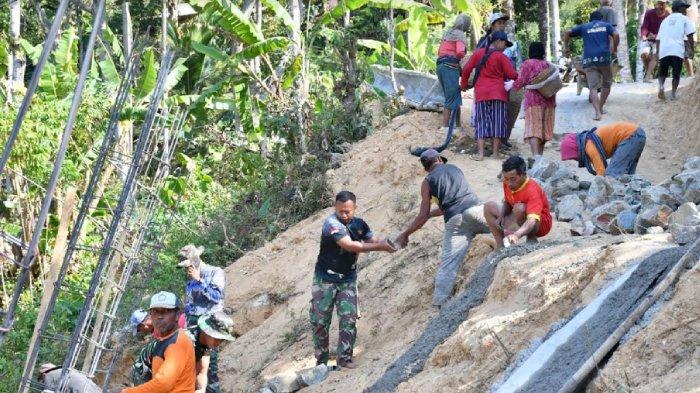 Prajurit TNI dan masyarakat Desa Selur bergotong royong mengerjakan salah satu sasaran tanggul penahan jalan.