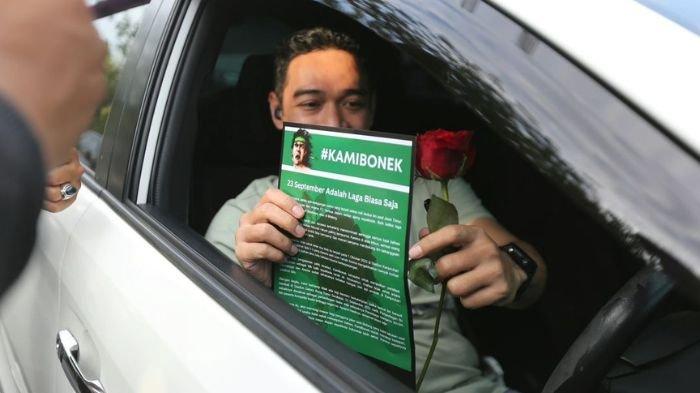 Seorang pengendar mobil mendapatkan selebaran dari Bonek dan bunga mawar dalam aksi simpatik jelang laga Persebaya Surabaya vs Arema FC