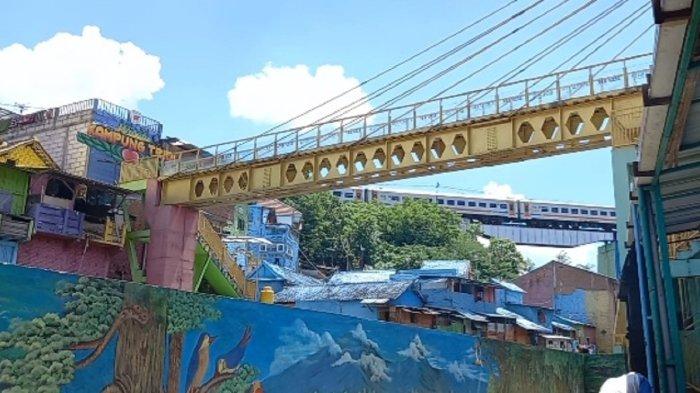 Melihat kereta api lewat di Kampung Warna Warni di Kota Malang, Selasa (10/1/2023).