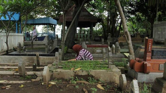 Seorang warga membersihkan makam di area pemakaman umum Bergota, Kota Semarang